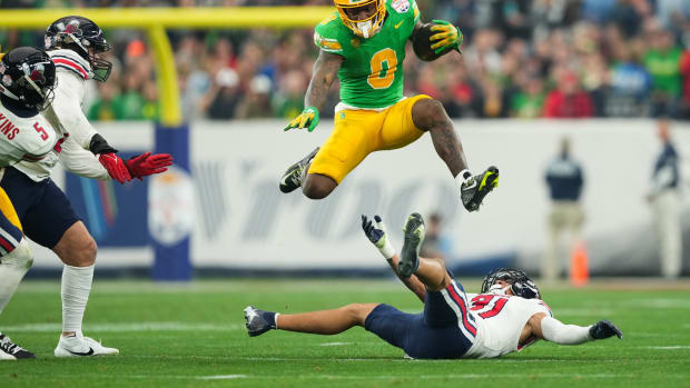 Jan 1, 2024; Glendale, AZ, USA; Oregon Ducks running back Bucky Irving (0) hurdles over Liberty Flames defensive back Brandon Bishop (6) during the second half in the 2024 Fiesta Bowl at State Farm Stadium. Mandatory Credit: Joe Camporeale-USA TODAY Sports  